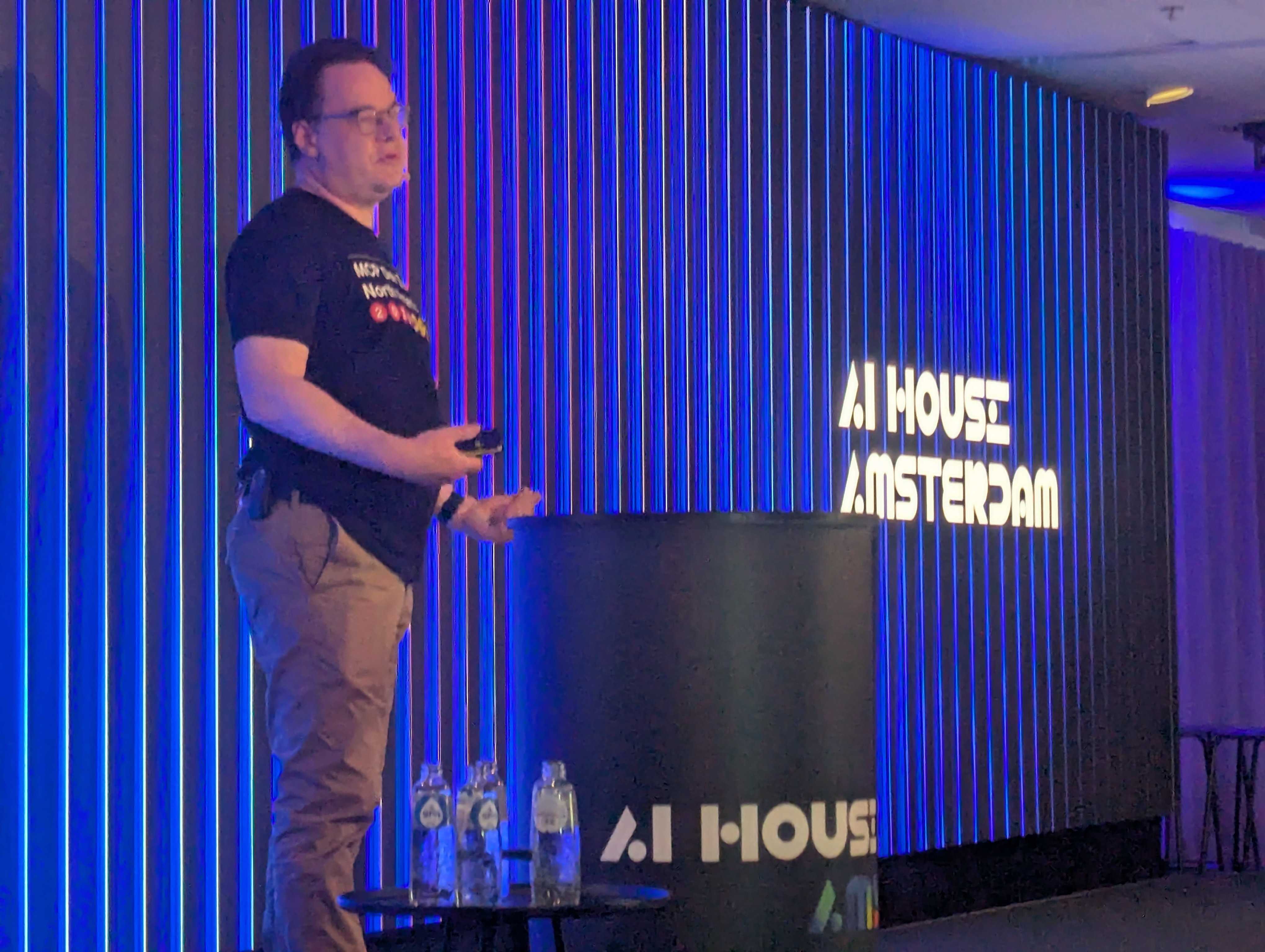 A speaker presenting to the MCP Release Party audience in front of the AI House Amsterdam logo